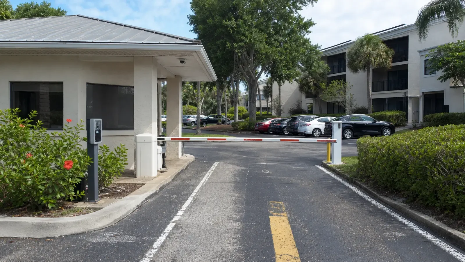 HOA entrance with a full-lane barrier, public callbox, pedestrian gate and high security camera.