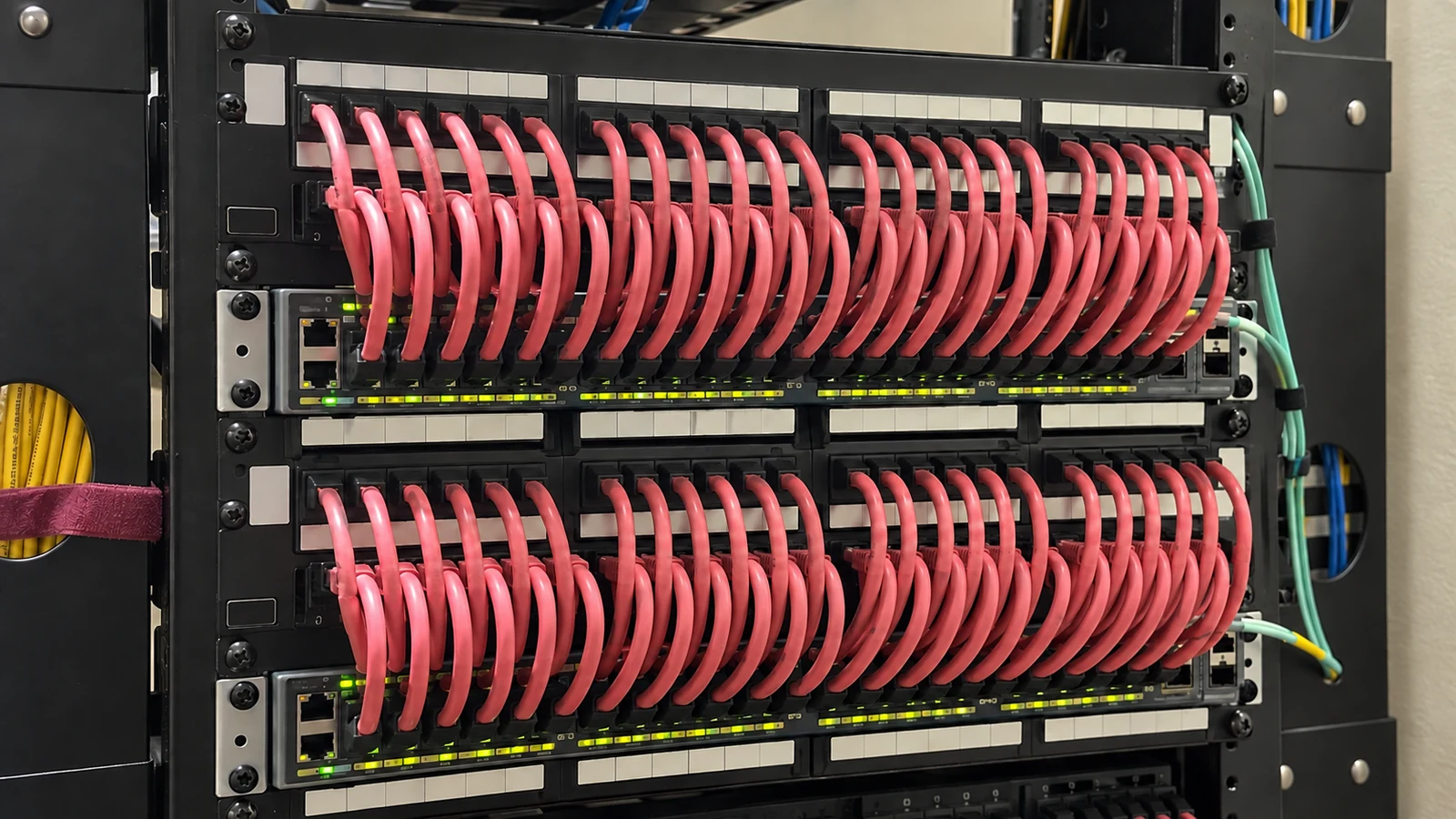 Separate red Ethernet patch cords connect rack-mounted patch panels and network switches.