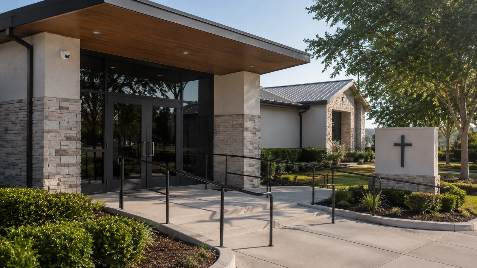 Small church entrance with double doors, an accessibility ramp, and an exterior sign