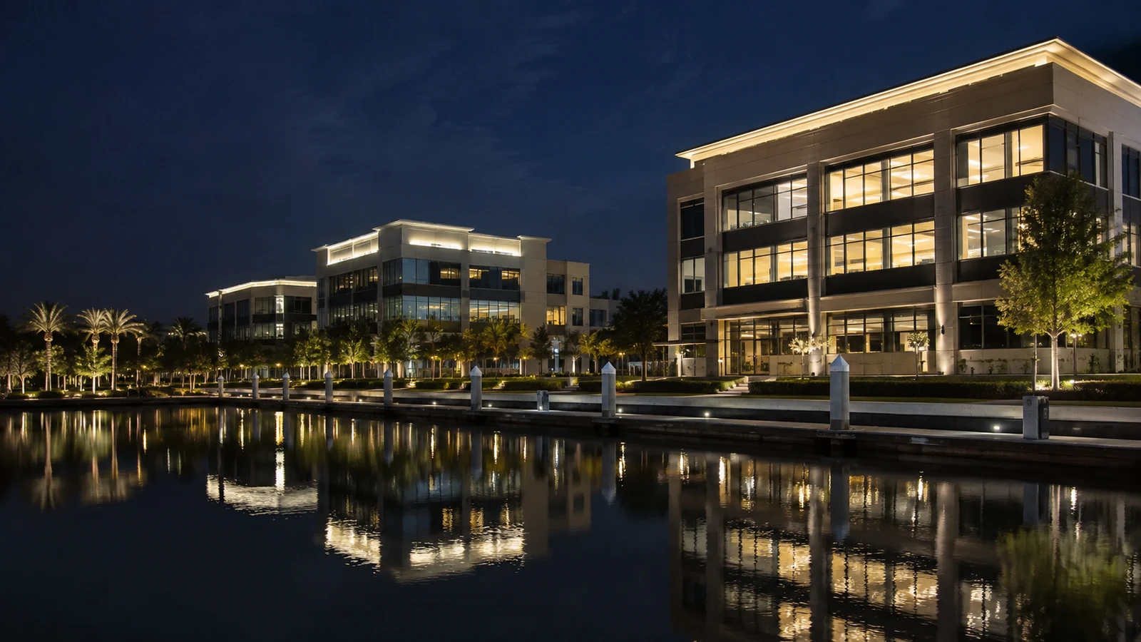 Illuminated office buildings reflected in dark waterfront water