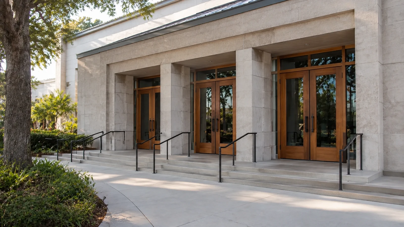 Contemporary United States church entry with three glazed wooden double-door bays, stone facade, steps and metal handrails
