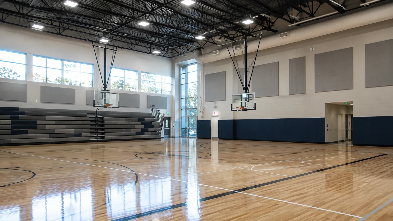 Empty indoor gymnasium and multi-use sports hall with hardwood court and bleachers